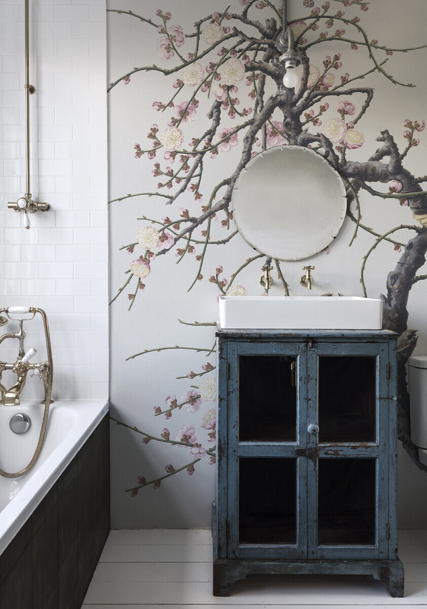 A wallpaper mural of pink cherry blossom in a rustic pink bathroom