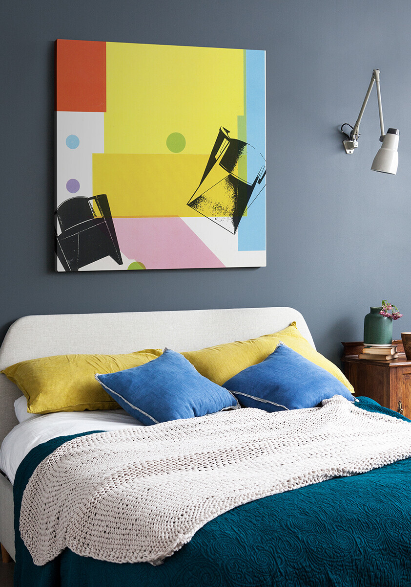 Retro 1986 furniture graphic, printed as a canvas in black on yellow and blue blocks of colour, hanging in a blue bedroom