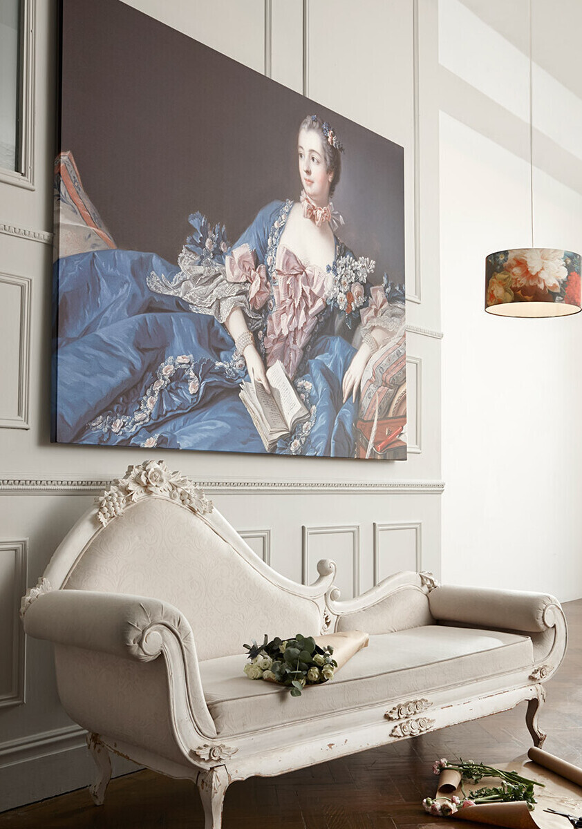 Painting of a lady in a blue dress with a cream sofa in front of the wall