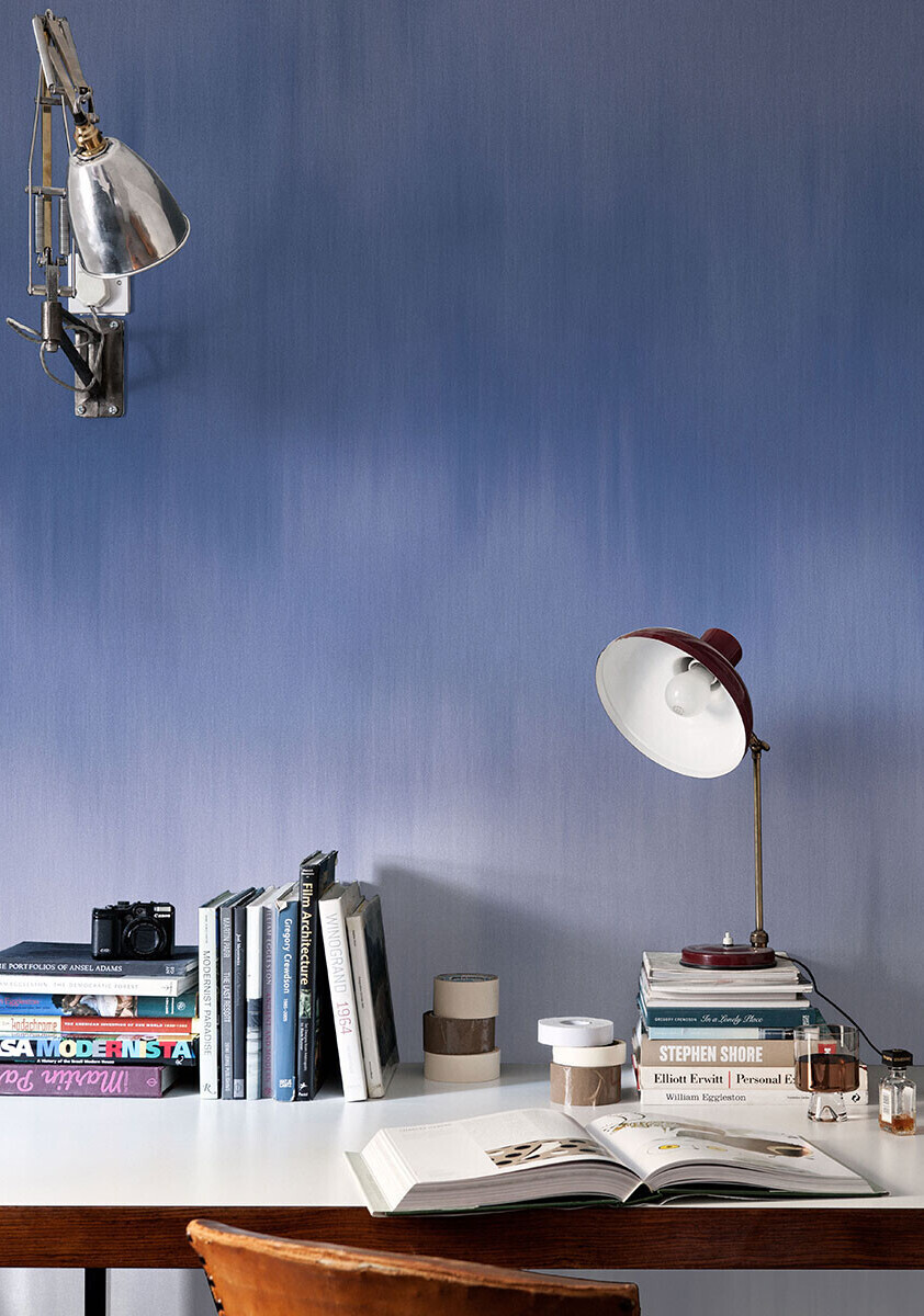 Blue ombre wallpaper mural with a desk, books and lamp